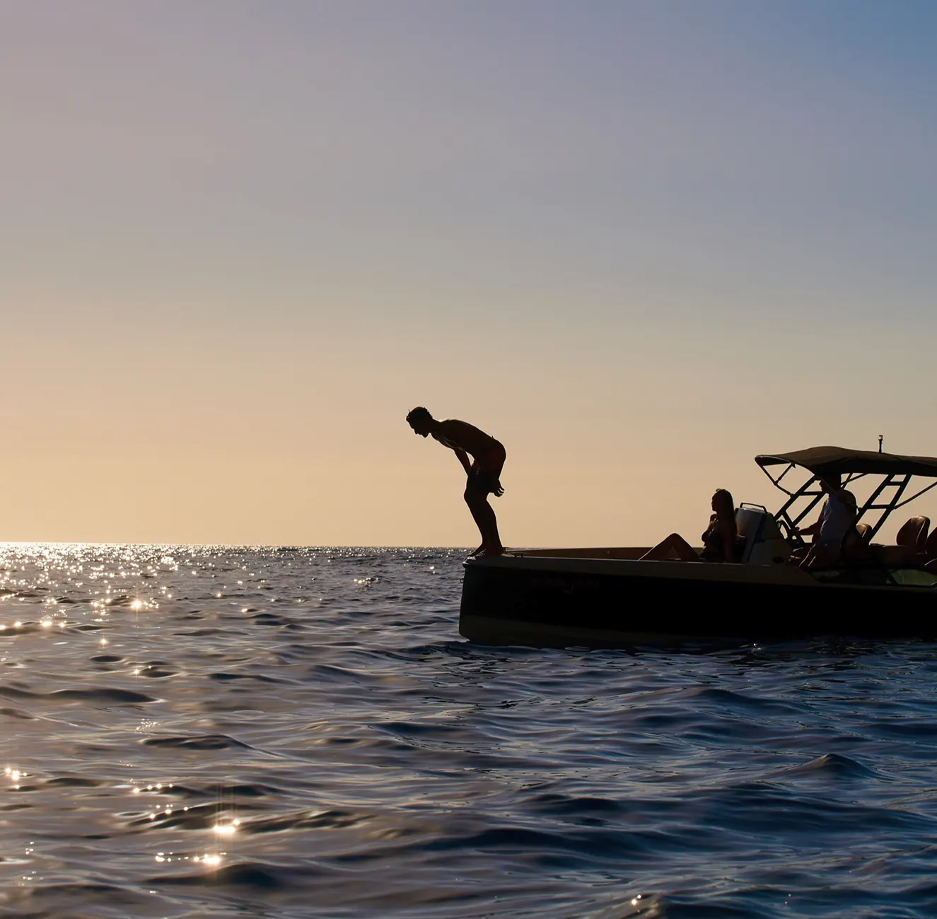 Diver plunging from compact boat into sunset-lit sea off southern Tenerife coast